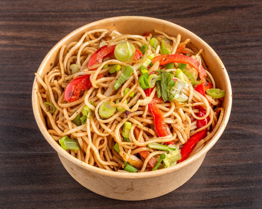 Veg chow mein noodles with bell pepper and green onion in a takeout bowl